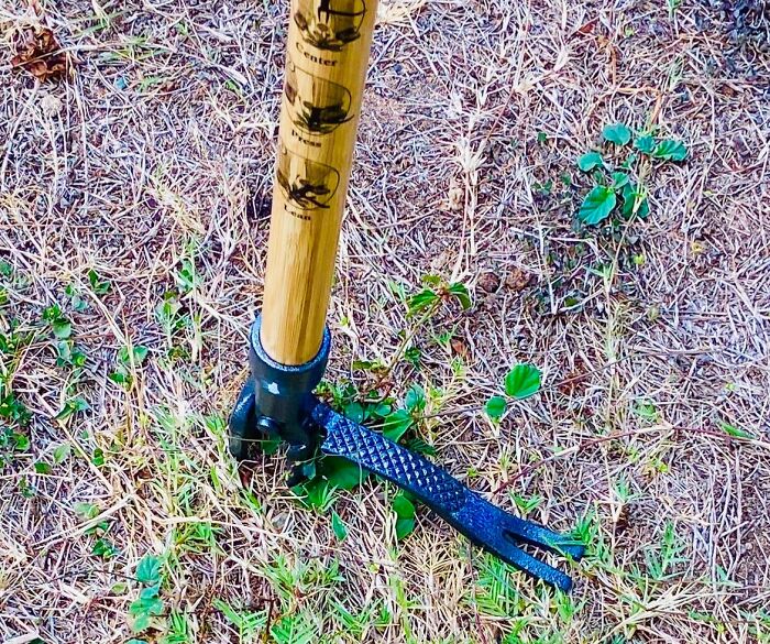 Garden tool with wooden handle and metal claw in dry grass, one of the most wished for items burning up Amazon this week