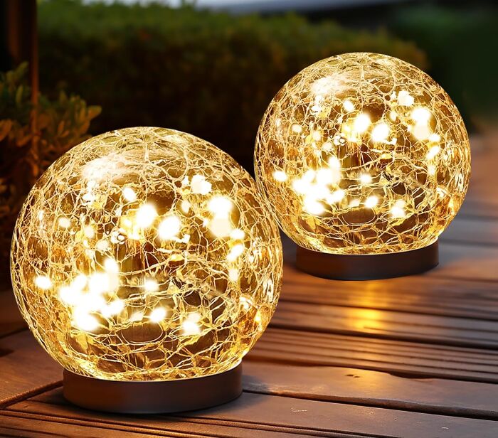 Glowing decorative orbs with warm string lights on outdoor wooden surface, popular wished for items on Amazon this week.