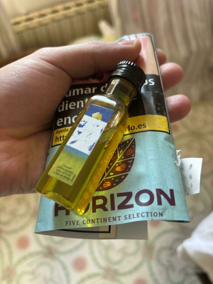 Hand holding a small bottle of yellow liquid and a folded brochure showcasing small but genius things some countries do.