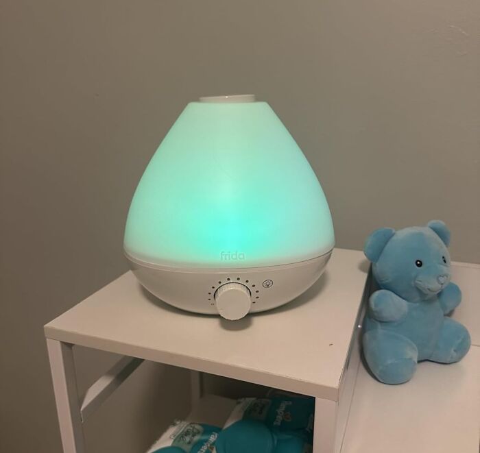 A glowing white essential oil diffuser on a shelf beside a blue teddy bear, popular among most wished for items on Amazon.