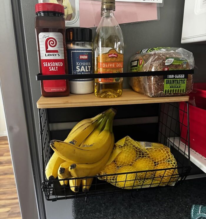 Kitchen organizer basket holding bananas, lemons, seasonings, olive oil, and bread, a popular Amazon most wished for item.