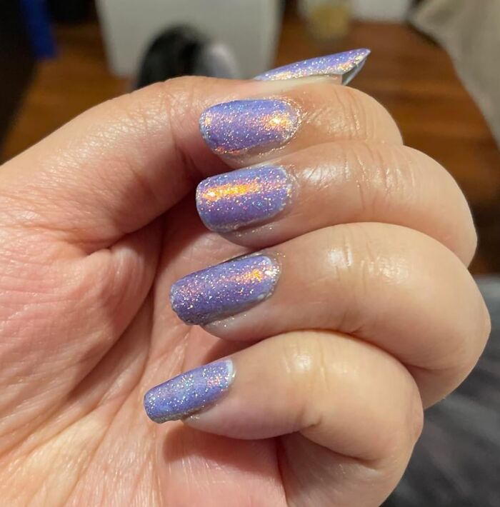 Close-up of hand with glittery purple nails showcasing one of the most wished for items burning up Amazon this week.