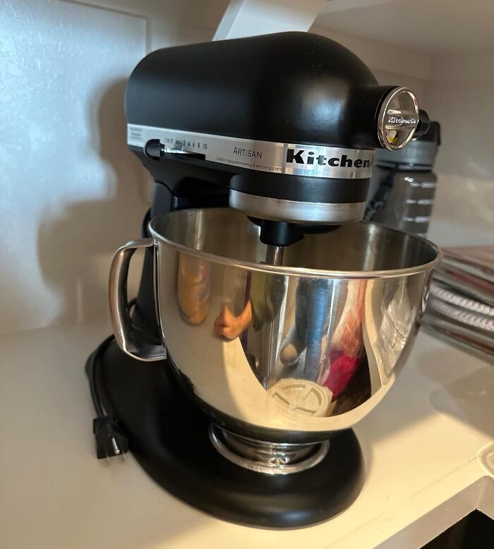 Black KitchenAid Artisan stand mixer with stainless steel bowl on kitchen counter among most wished for Amazon items.