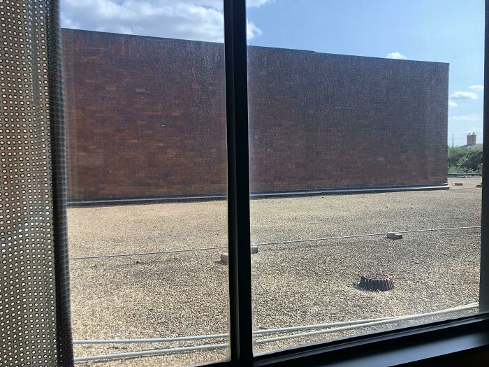 View from hotel window showing a plain brick wall and gravel rooftop, illustrating hotels messed up examples shared online.