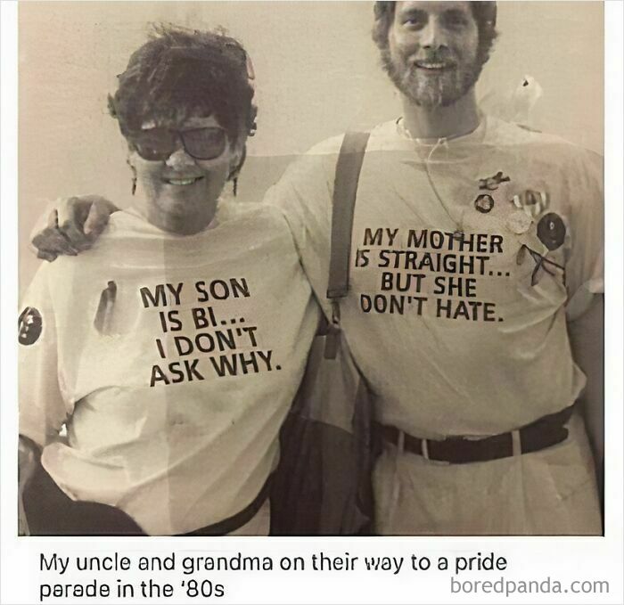 Two people wearing 1980s LGBTQ+ themed shirts at a pride parade, promoting acceptance and bi visibility.