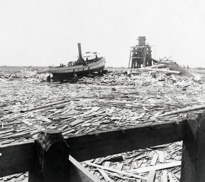 Boat stranded on debris-covered shore showing aftermath of natural disasters larger than people could cope with in the last century