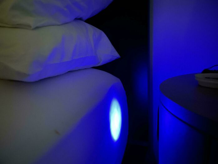 Blue light shining on a hotel bed and pillow, illustrating one of the times hotels messed up so bad guests vented online.