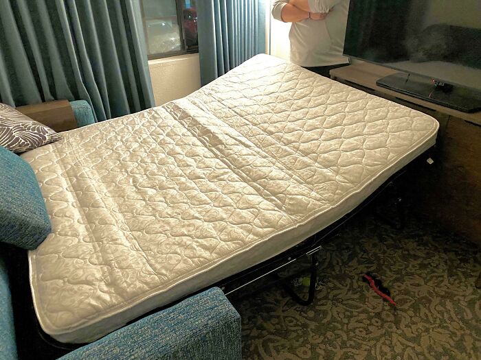 Hotel mattress bent awkwardly on a fold-out bed frame in a room, showing a major hotel mess-up complaint.