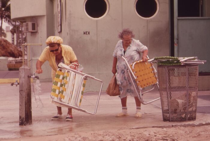 Two women in Florida in the 1970s holding beach chairs near a water fountain, capturing breaking barriers moments.