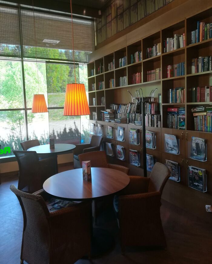 Cozy reading corner with round tables, wicker chairs, hanging lamps, and bookshelves showcasing genius small things some countries do.