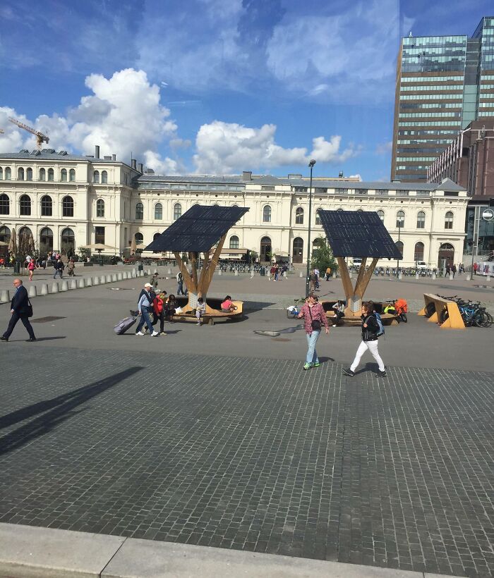 Public square with solar panel benches showcasing small genius things some countries do for sustainability and innovation.