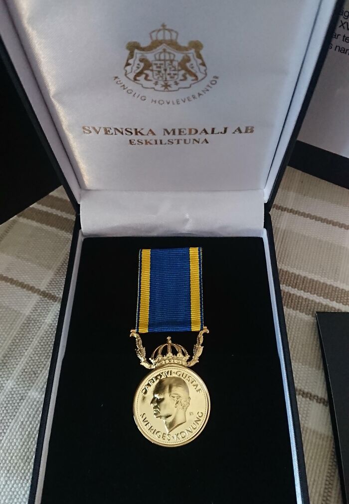 Gold medal with blue and yellow ribbon in a black case, showcasing small genius things some countries do for recognition.