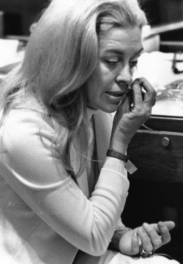 Black and white photo of a woman in Florida in the 1970s breaking barriers, wiping tears while seated indoors.