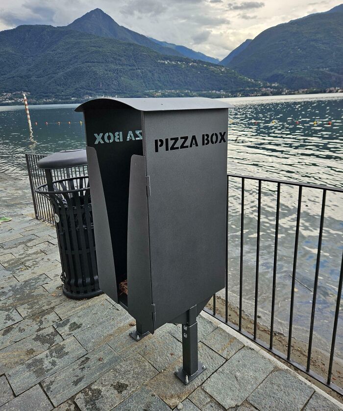 Innovative pizza box recycling bin by the lakeside, showcasing small genius things some countries do for better waste management.