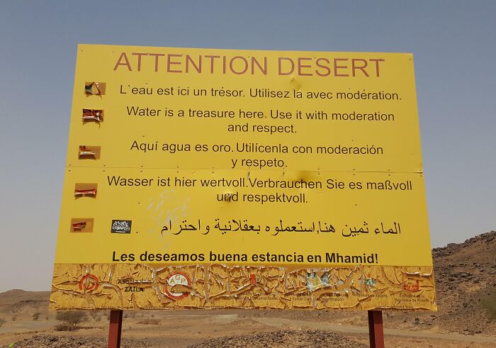 Desert water conservation sign in multiple languages, highlighting small genius things some countries do for resource respect.