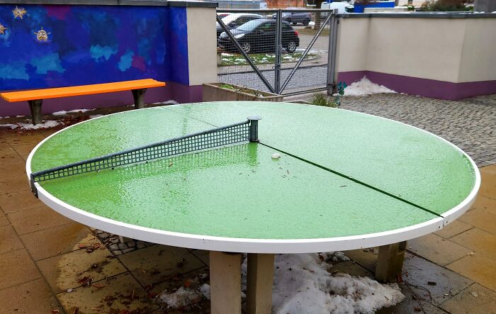 Outdoor round green ping pong table with net in a public space showcasing small genius things some countries do.
