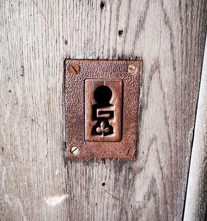 Rustic metal keyhole plate on a wooden door showcasing small genius things some countries do for smart design solutions.