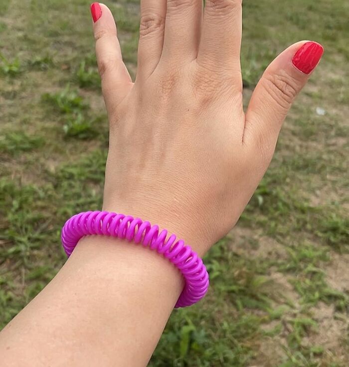 Hand wearing a bright pink spiral bracelet outdoors, showcasing one of the products for specific problems solution.