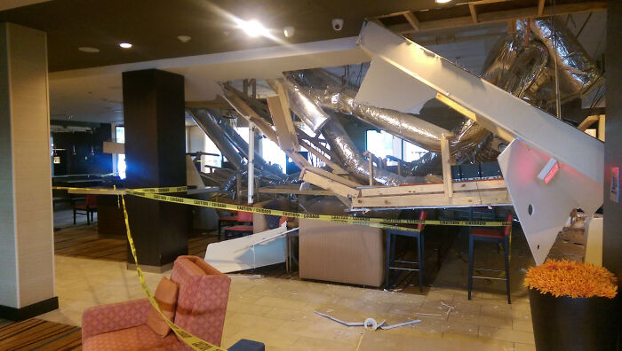 Hotel lobby with collapsed ceiling and caution tape showing a major hotel mess up that guests had to vent about online.