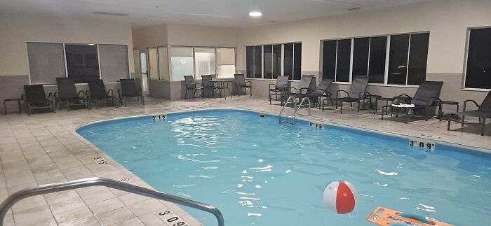 Indoor hotel pool with uneven water level and scattered pool toys, showcasing a hotel mess-up seen by guests online.