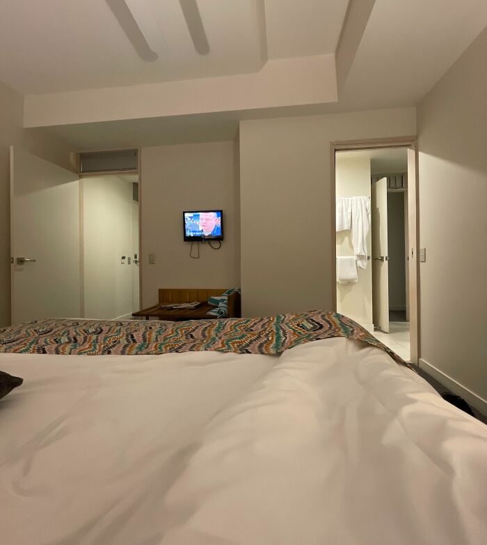 Hotel room with an unmade bed and small TV mounted on the wall, showcasing one of the times hotels messed up badly for guests.