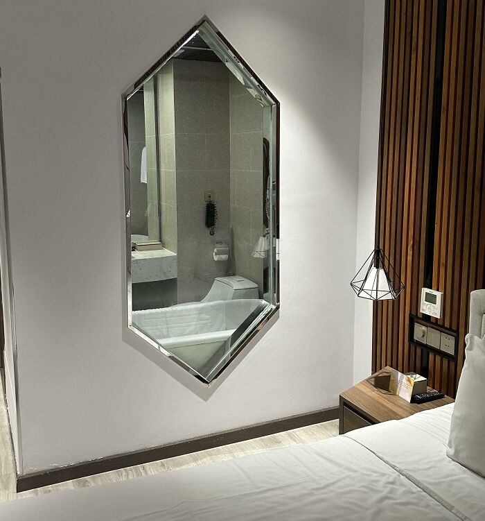 Hotel room with a mirror showing a bathroom, highlighting one of the times hotels messed up with poor design choices.