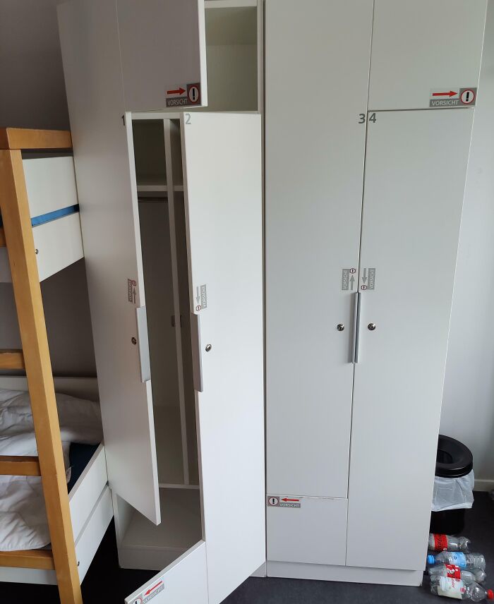 White hotel lockers with multiple doors labeled with contradictory warning stickers causing confusion, showing hotels messed up.