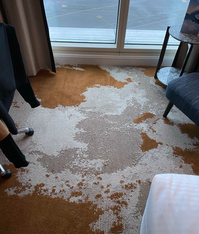 Hotel room carpet with worn and stained areas near window, showcasing one of many hotel mess up moments shared online.