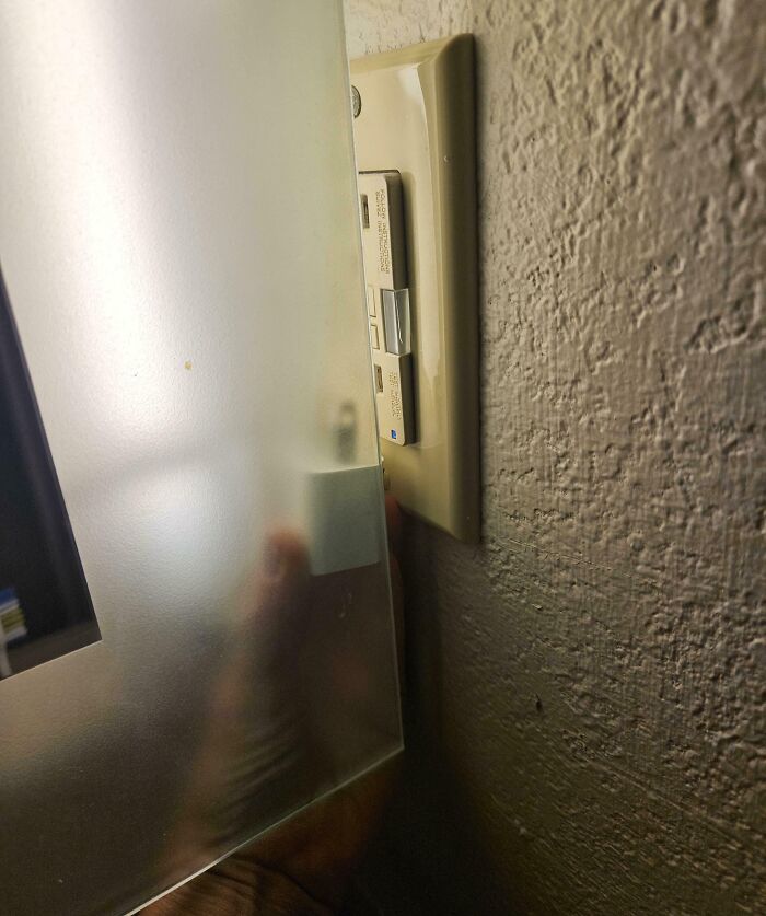 Light switch in a hotel room blocked by a frosted glass panel, showcasing a hotel design fail from guest experiences online.