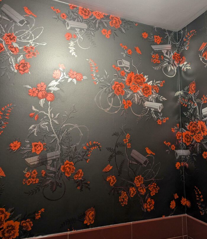 Dark floral wallpaper in a hotel room with hidden security cameras blending into the design, an example of hotels messed up.