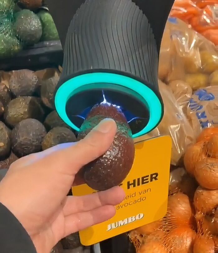 Hand using a device to check avocado ripeness, showcasing genius small innovations some countries implement immediately.