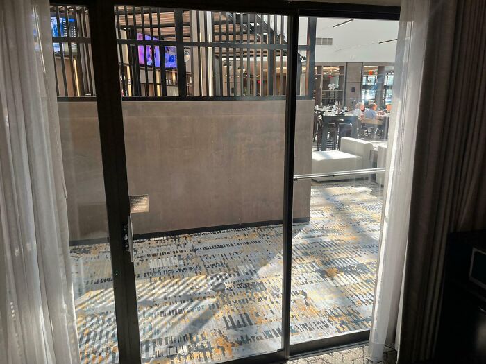 Hotel balcony with no outdoor space, showing an indoor area behind glass doors, a common hotel mess-up shared online.