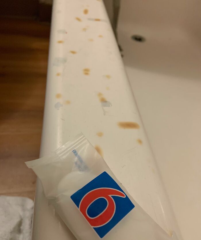 Rust stains and chipped paint on a hotel bathtub edge with a wrapped soap bar, showing a hotel mess-up.
