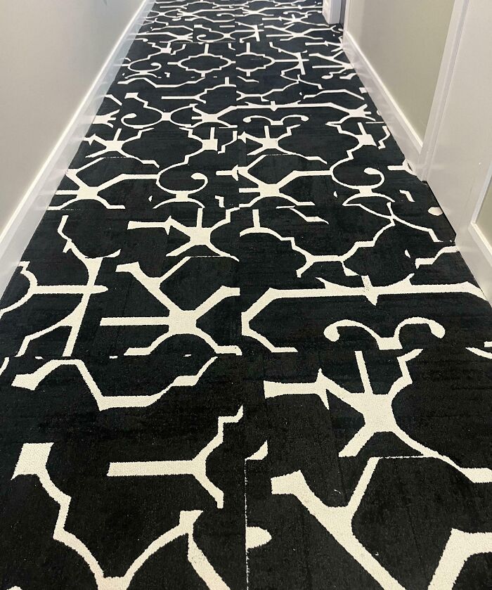 Black and white patterned hotel carpet with mismatched sections causing a visual design error in the hallway.