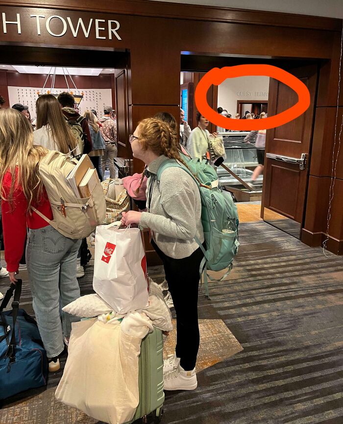 Hotel guests standing in a crowded lobby next to a door with a confusing sign, showcasing hotel mess-up frustration.
