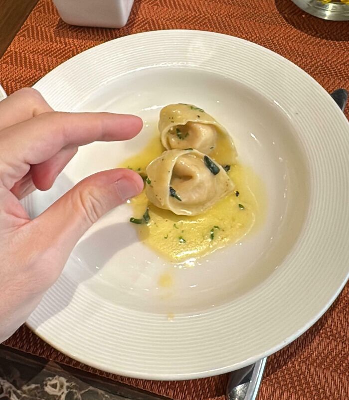 Small hotel food portion with two pieces of tortellini on a white plate, showcasing hotel food failures online complaints.