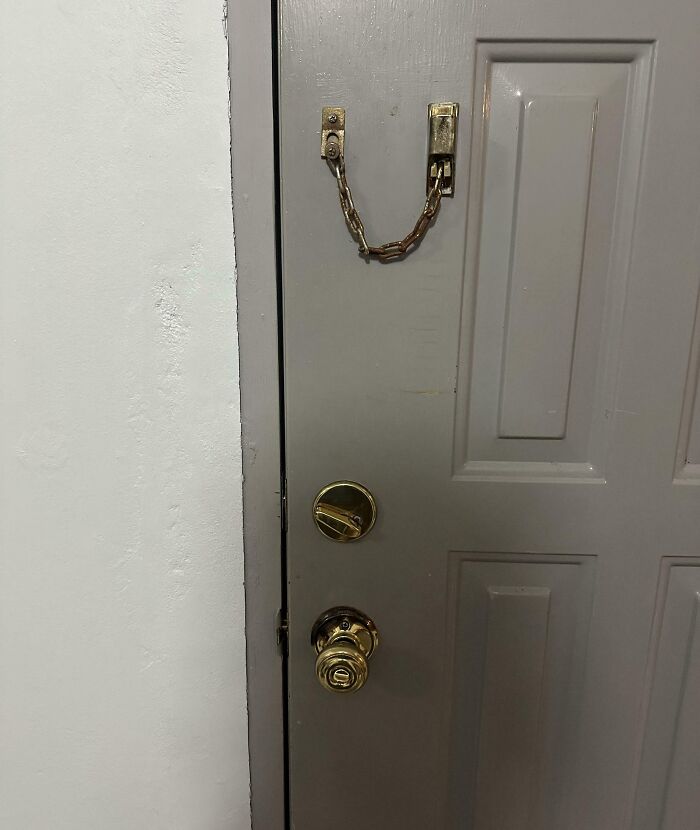 Hotel door with broken chain lock and misaligned frame, showcasing a poor security fail in hotel accommodations.