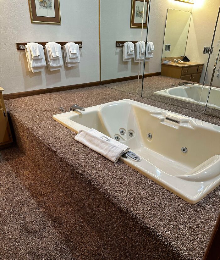 Hotel bathroom with carpeted jacuzzi tub platform and mirrored walls, showcasing a major hotel design mess-up.