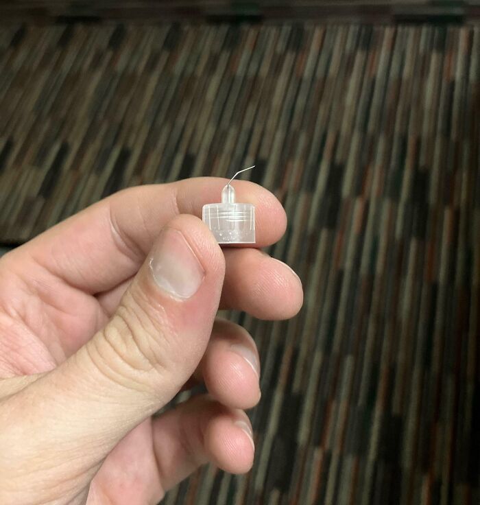 Hand holding a tiny hotel sewing kit container with a single needle, one of many hotel fails shared online.