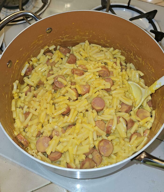 Pot of cheesy macaroni and hot dogs on a stove, showcasing wholesome and funny dads doing their best cooking.
