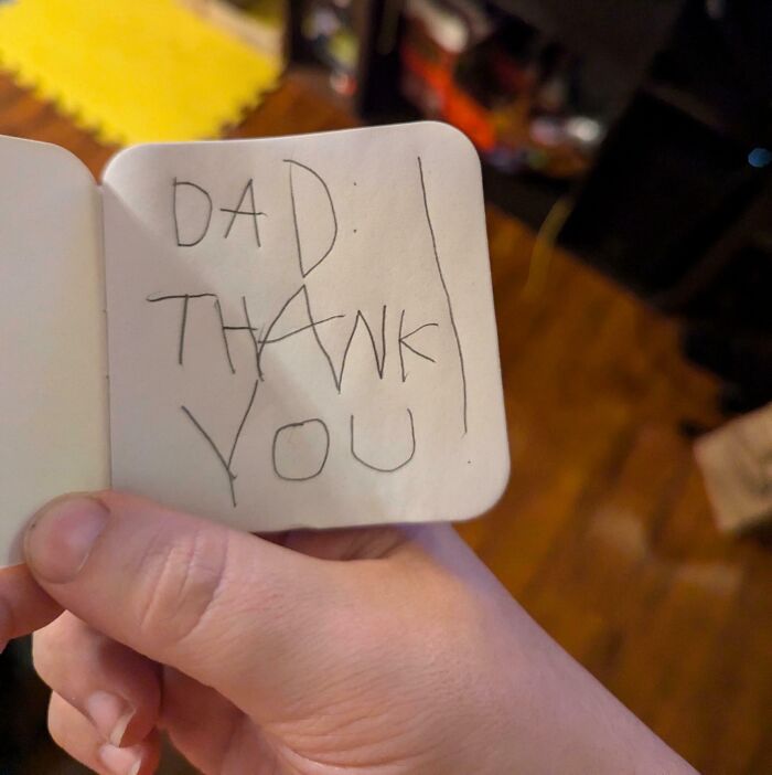 Hand holding a small handwritten note saying thank you, capturing wholesome dads doing their best moment.