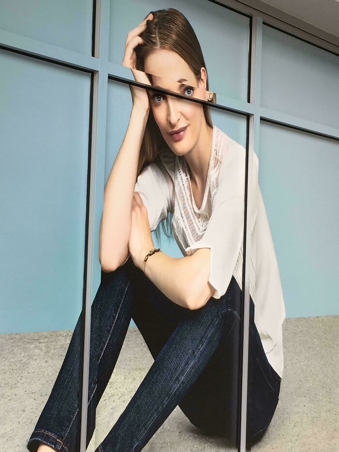 Advertising fail with distorted woman’s body caused by misaligned glass panels on storefront display.