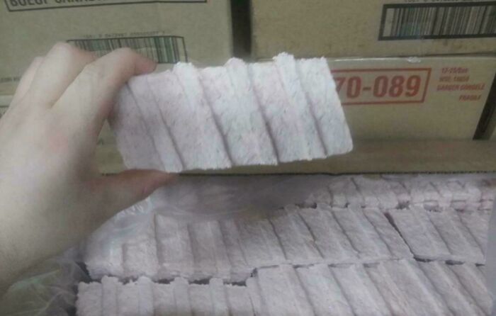 Hand holding a fascinating and extraordinary textured pink snack bar from a box, showcasing unique patterns.