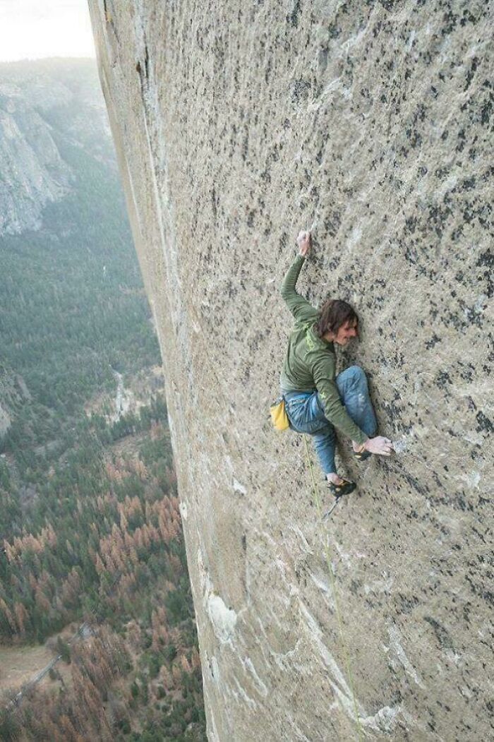 Man climbing an extraordinary and fascinating steep rock face high above a forested valley, showcasing adventurous outdoor pursuits.