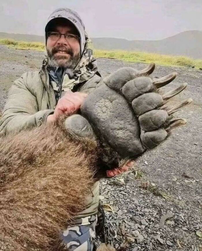 Man holding a giant bear paw showcasing one of the extraordinary and fascinating things people saw and wanted to show others.