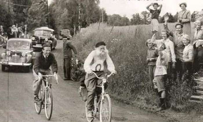 Crowd watching two cyclists on a rural road in a vintage black and white photo showing extraordinary moments people saw.