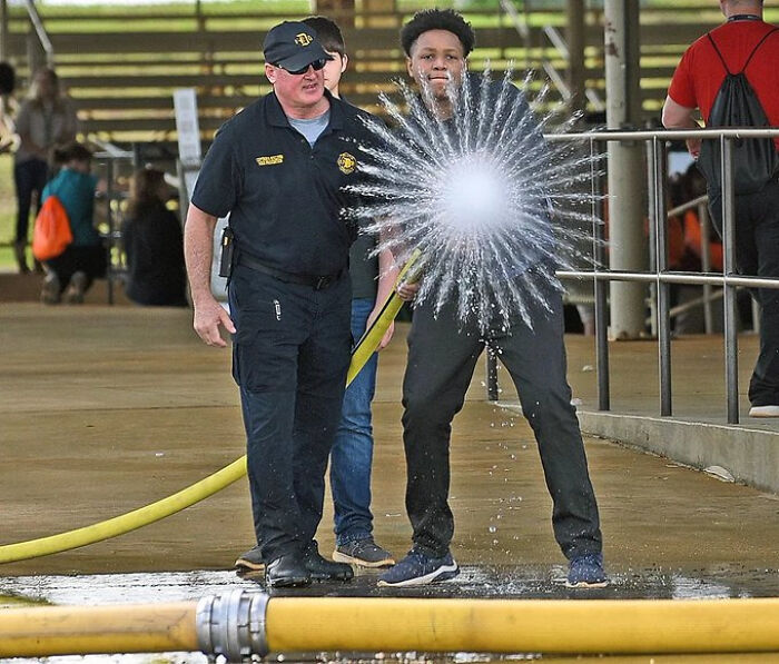 Man holding a bursting water hose with a security officer nearby, an extraordinary and fascinating sight.