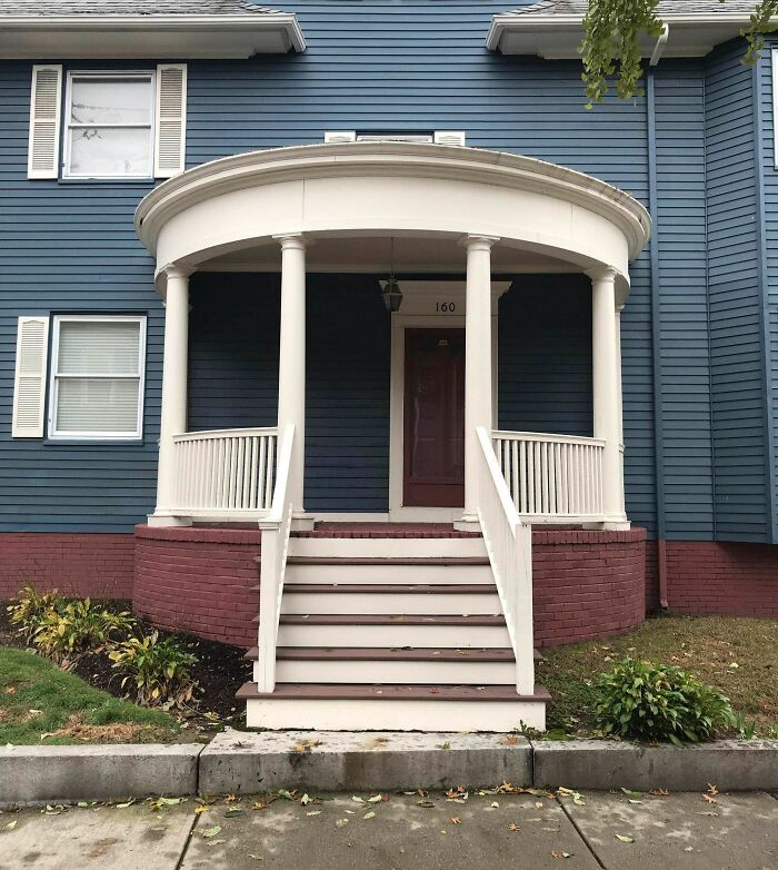 Blue house entrance with uneven porch steps, white railings, and a round roof, showing imperfections that may annoy people with OCD.