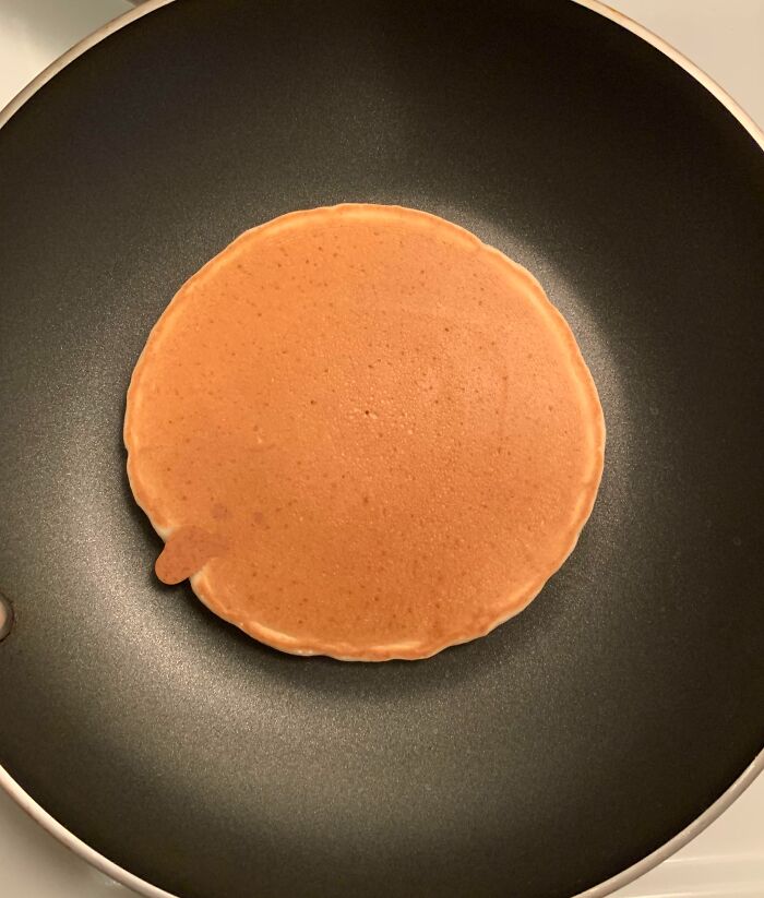 Imperfect pancake with a small uneven edge cooking in a nonstick pan, showing a common annoyance for people with OCD.