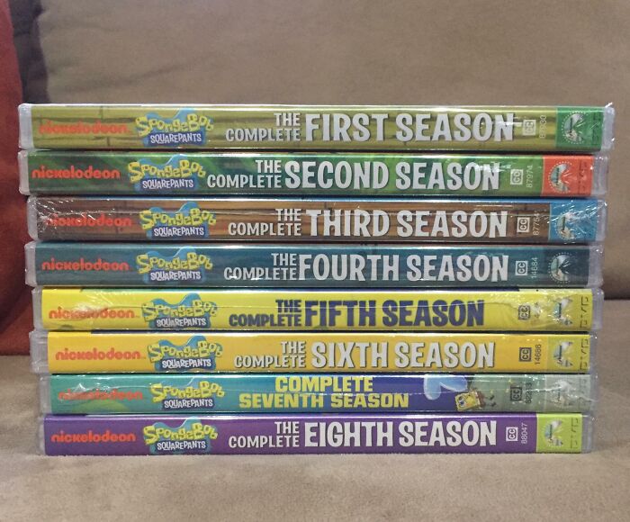 Stack of SpongeBob SquarePants DVD seasons aligned on a couch, showing imperfectly stacked cases that may annoy people with OCD.